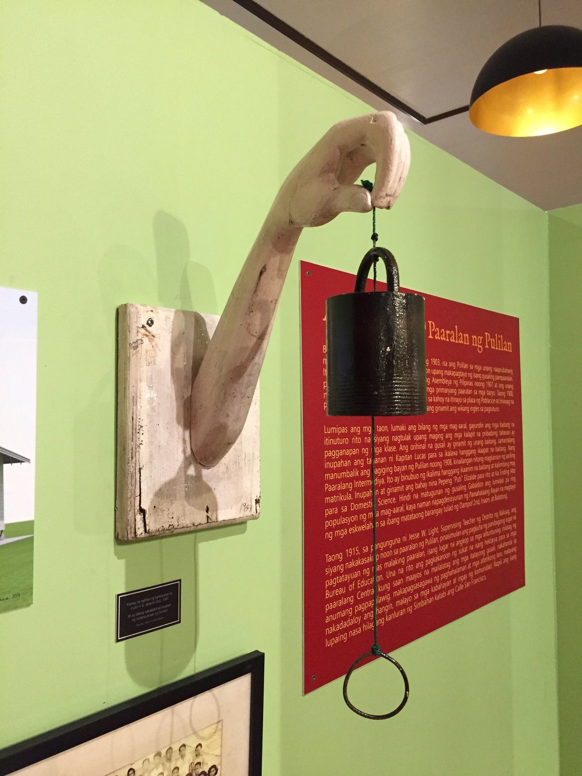 Carved bell holder in the shape of an arm.